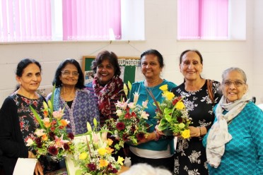 Group of ladies of different ethnicities smile holding flowers
